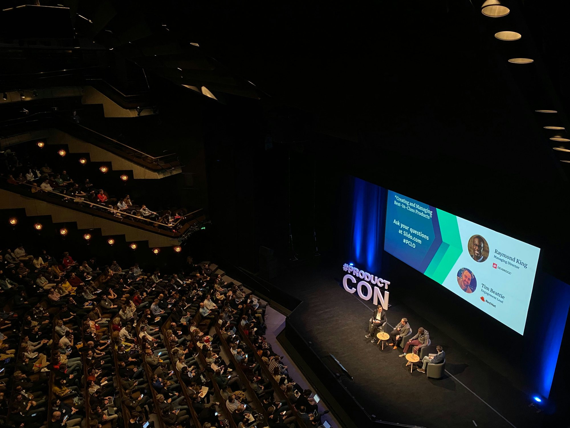 Table ronde sur scène devant une grande salle de conférence